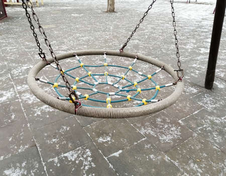 Round rocking chair, hammock made of hemp ropes with support between the columns on the playground.