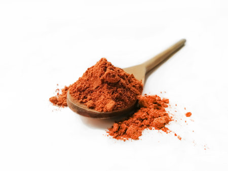 Hot red pepper in a wooden spoon on a white background. Scattered red pepper.の写真素材