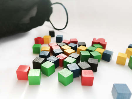 Colored cubes made of wood on a white background. Next to it is a black pouch with a puff. Cubes and...