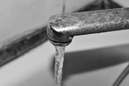 Black and white photo. Water runs from the rusty tap. Old faucet in the bathroom. The texture of the...