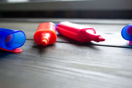 Two open markers lie on a wooden table. Side view of the pink and orange markers. Text highlighters without caps on a wooden table.の写真素材