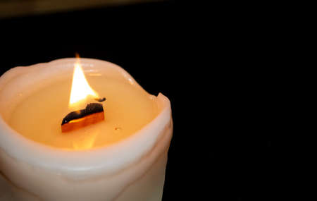A candle burns in a dark room. candle close-up in the dark. Light in the darkness. Candle fire. Wooden felt in a candle.の写真素材