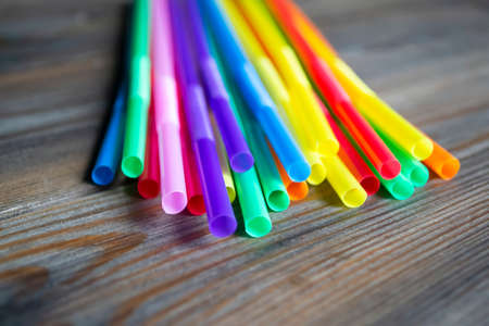 Cocktail straws for drinks are laid out on a wooden table. Wooden background and plastic straws for drinks. Eco-friendly straws. Colored straws.の写真素材
