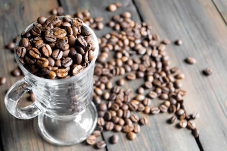 There are a lot of coffee beans in the glass cup. Coffee on the table. Coffee beans in Czech. On a...