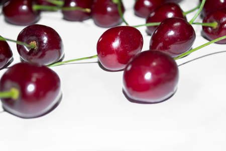 Bright cherry on a white background. The contrast of red berries and white canvas. Summer cherry berries on white.の写真素材