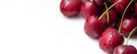 There are red cherries on a white background. Red cherry berries contrast with the white background. cropped photo.の写真素材