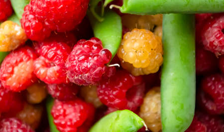 Green peas in pods with raspberries. Red and yellow raspberries, green pea pods. summer berries and legumes.の写真素材