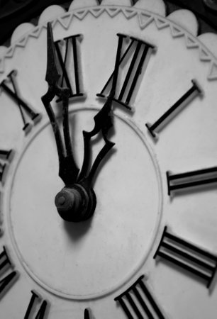 The clock shows without five minutes twelve. Hands of the clock at 11:55. Roman chickens. Carved arrows. Openwork hands on the clock. old clock.の写真素材