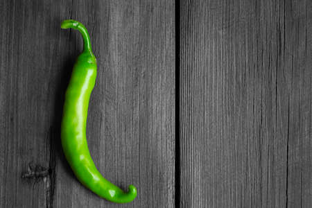 Green, hot pepper on the gray background of the tree. gray wood and green chili pepper. The contrast of the green vegetable on the gray tree. chili pepper. Green pepper pod.の写真素材