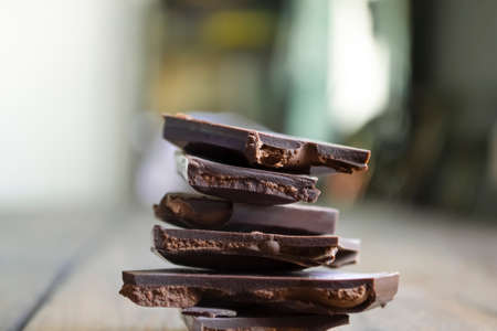 Dark chocolate with filling. a wooden table and a stack of chocolate. A stack of chocolate slices on...