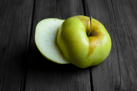 An apple cut into two halves lies on a wooden table. Shooting from above - two halves of an apple...