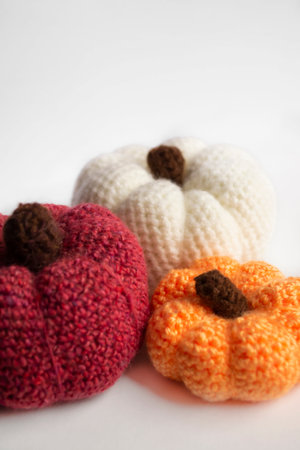 On a white background there are three crocheted pumpkins. White, orange and red pumpkins crocheted. the autumn scenery is pumpkins.の写真素材