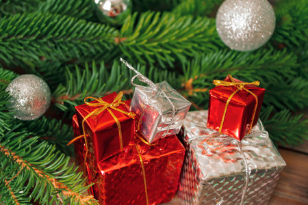 New Year's gifts next to the Christmas tree. On the wooden table are gifts with a Christmas tree....