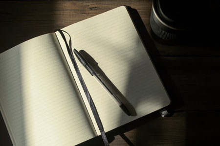 Notebook for notes with a black pen on a wooden table, next to a cup of black color. Photos with...