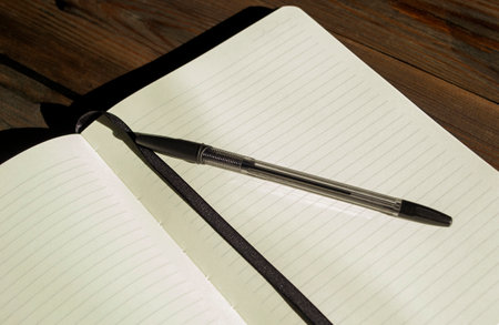 Notepad with a pen on a wooden table. Workbook with pen. notebook in line with blank pages, on the...