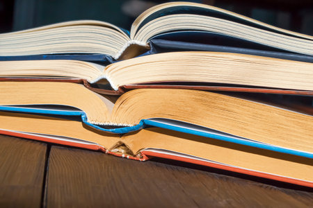 A stack of open books on a wooden table. On the table are four open books. side view of the books.の写真素材