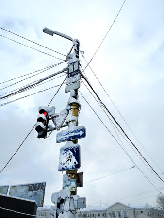 Road signs on a lamppost. Road signs and traffic lights on the pole are covered with snow. The pillar with signs in winter is covered with snow. the blizzard covered the traffic lights with snow.の写真素材