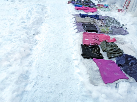 In the snow, people sell things. The clothing market right on the ground is winter. On the snow are sweaters for sale. Flea market in winter.の写真素材