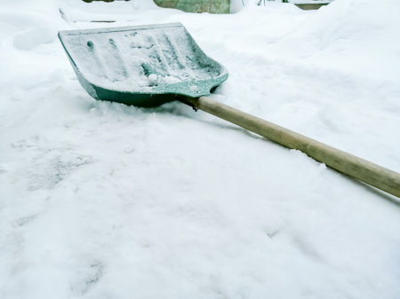 The shovel for snow removal is lying down. ON the snow is a shovel for winter work. Snow removal in the yard in winter.の写真素材
