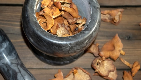Dry mushrooms on a wooden table. On the table there is a stone mortar to grind dry mushrooms. Mushrooms for grinding in a mortar. Dry mushrooms.の写真素材