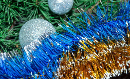 Festive decorations in the colors of the flag of Ukraine - yellow-blue. Tinsel on the Christmas tree is yellow and blue against the background of a spruce with silver balls. New Year and Christmas.の写真素材