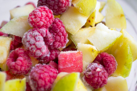 Frozen vegetables in a bowl. in a glass bowl are frozen pieces of apples and raspberries. winter vitamins - frozen fruits.の写真素材