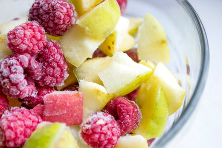 Frozen vegetables in a bowl. winter vitamins - frozen fruits. in a glass bowl are frozen pieces of apples and raspberries.の写真素材