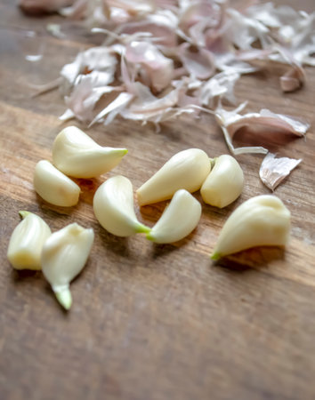 Peeled garlic next to the husk. garlic cloves peeled from the husk. ON a wooden board garlic next to the husk.の写真素材