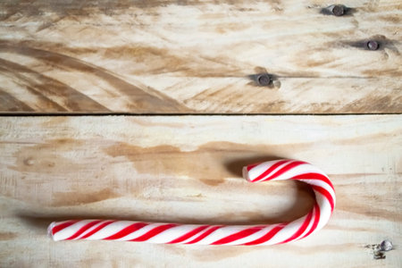 Christmas cane on a wooden table. A cane cane striped on a table made of wood. Christmas and new year sweets.の写真素材
