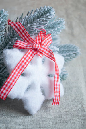 On a spruce branch in the snow hangs a snowflake. a toy in the form of a snowflake with a bow on a spruce branch. Christmas and New Year - Christmas tree decorations.の写真素材