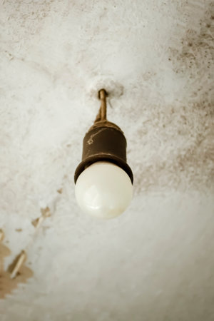 A LED light bulb hangs from the ceiling. An economic light bulb hangs from the ceiling. there is a light bulb on the old ceiling for lighting.の写真素材