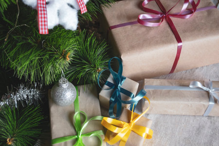 Next to the Christmas tree are packaged gifts. Under the festive tree are gifts tied with colored ribbons. Christmas and New Year gifts.の写真素材