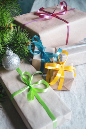 Packaged gifts with colored ribbons lie under the Christmas tree. Gifts under the tree.