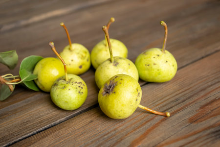 Paradise apples of green color on a wooden table. Apples look like small pears. There are small apples on the table.の写真素材