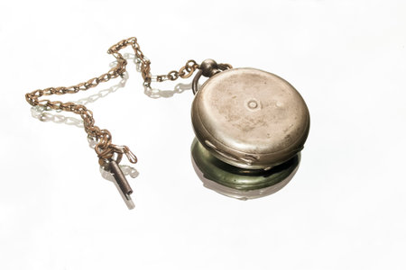 Pocket watch on a mirror background. The mirror reflects a pocket watch. vintage clock. pocket, made of silver with a key for winding.の写真素材
