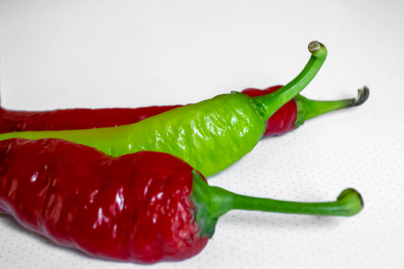 Hot pepper on a white background. On the white there are two red and one green pepper pods. Chili peppers on a white background. Three peppers. Green and red hot pepper.の写真素材