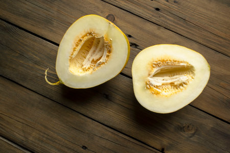 Two halves of a melon on a wooden table. Two parts of a melon. A young, sweet melon without seeds.の写真素材