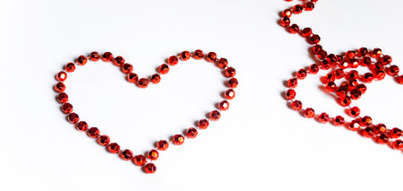 The heart is lined with red beads on a wooden table. Valentine's Day - valentine on the table with your own hands. A heart is lined with beads on the table.の写真素材