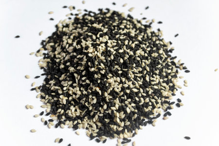 On a white background is a mountain of sesame. Black and white sesame lie on a slide. Mixed white and black sesame on the table.の写真素材