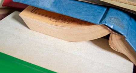 The open book lies covered up. An abandoned book with a blue cover. Piled up books. Old, abandoned books.の写真素材