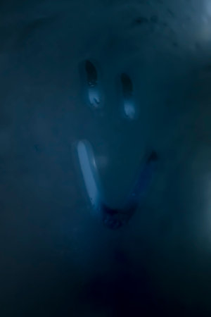 A funny face is painted on the fogged glass. Smiley face on the fogged glass. The mirror is sweaty - drawing, eyes and smile.の写真素材