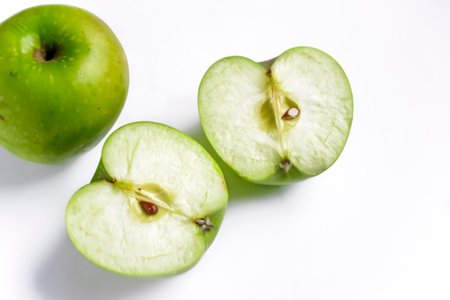 Two halves of a green apple on a white background. On the white is a chopped green apple. I block green cut. healthy fruits.の写真素材
