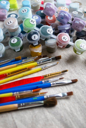 Colored brushes and paints for drawing. Brushes lie next to colored paints. Paints for drawing together with brushes on linen fabric.の写真素材