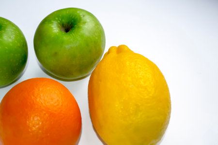 Orange, lemon and green apple on a white background. On a white background lie useful fruits.の写真素材