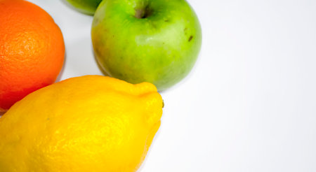On a white background lie useful fruits. Orange, lemon and green apple on a white background.の写真素材