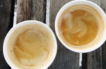 Americano in paper cups on the street. Two coffees with foam on a wooden bench, top view.の写真素材