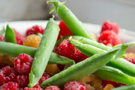 Fresh, summer berries - green peas in pods and red raspberries. Healthy legumes are in the summer. Green peas are in the same bowl with red raspberries.の写真素材
