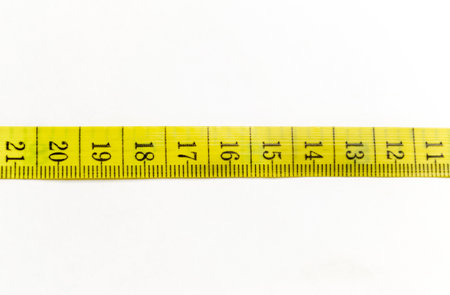 A yellow meter on a white background. On the table is a long yellow ribbon with measurements for the seamstress.の写真素材
