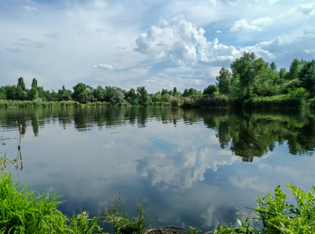 Beautiful lake surrounded by trees. Clouds are reflected in the lake.の写真素材