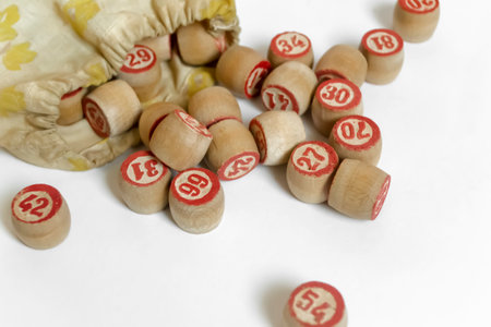 Wooden bingo barrels fell out of the bag. Barrels with numbers for lotto on a white background. Old barrels with numbers made of wood.の写真素材